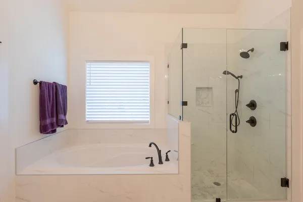 a bathroom with a tub shower and window