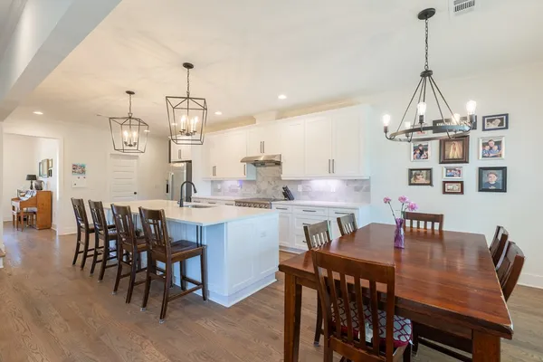 a dining room with stainless steel appliances a table chairs and a kitchen view