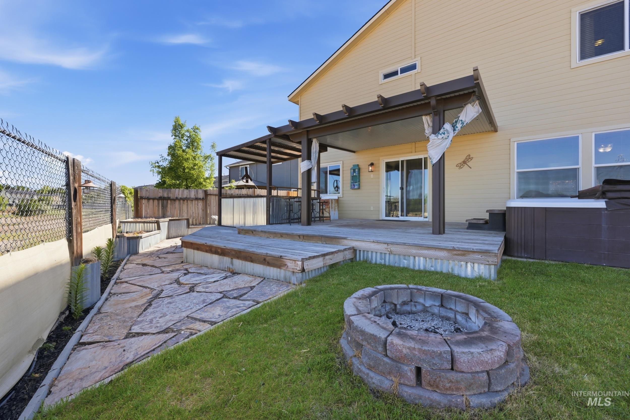 4855 South Chex Way Boise, ID 83709 - Photo 27 of 47 Expansive outdoor living area featuring a covered pergola patio, a stone paver pathway, a built-in fire pit, a raised wood deck, and a hot tub