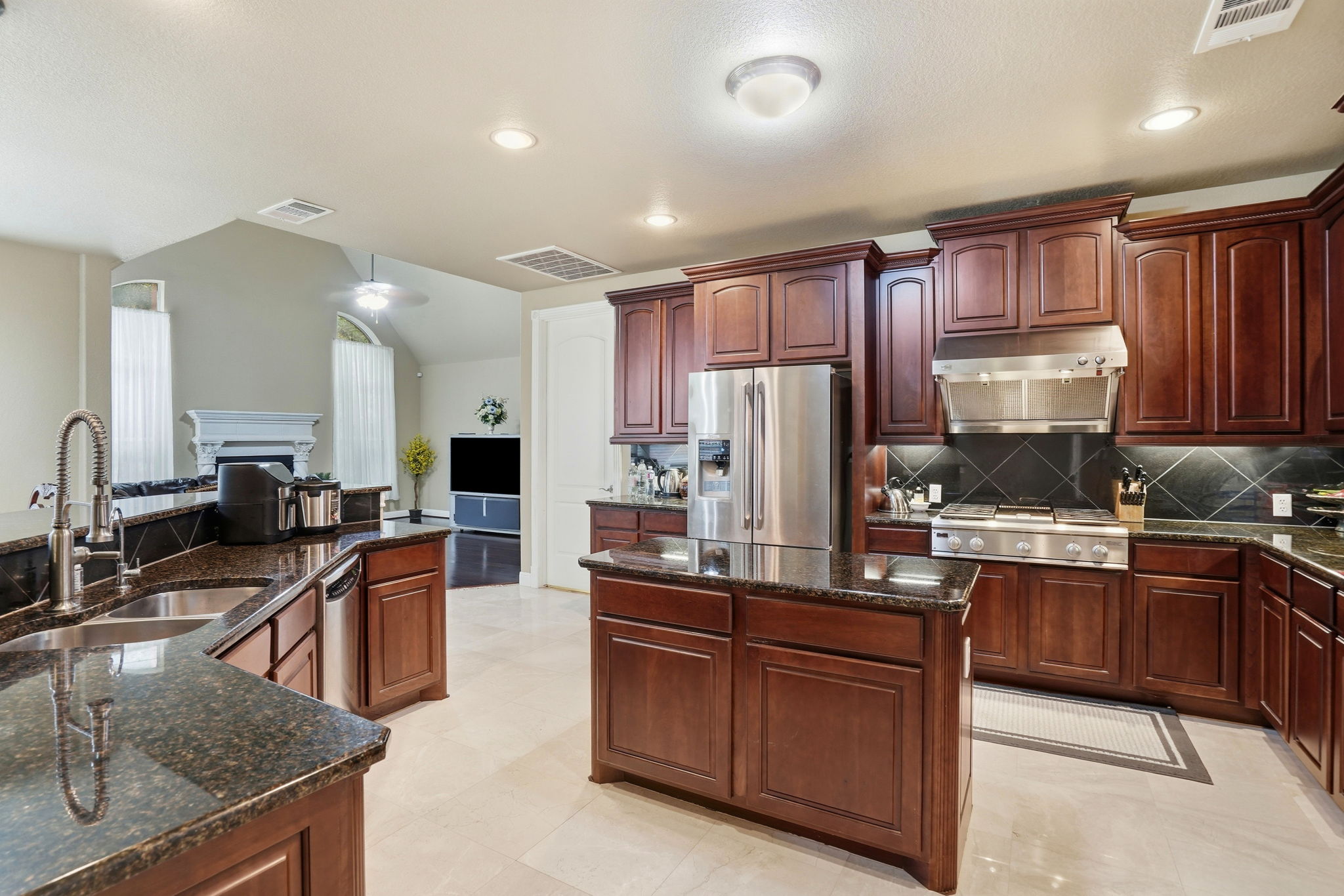 222 Vailco Lane Austin, TX 78738 - Photo 19 of 39 Gourmet kitchen featuring dark wood cabinetry, granite countertops, an undermount sink with a gooseneck faucet, stainless steel appliances, and a central island