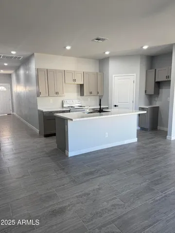 a large kitchen with kitchen island a sink a stove a refrigerator and white cabinets with wooden floor