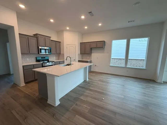 a large kitchen with stainless steel appliances granite countertop a stove a sink and a refrigerator