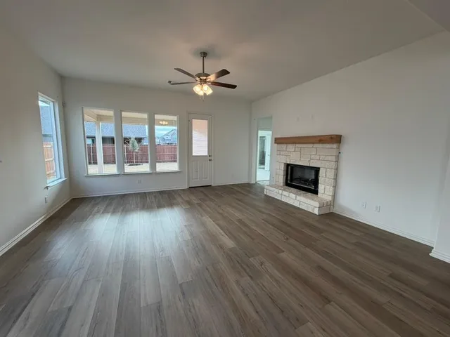 an empty room with wooden floor fireplace and windows