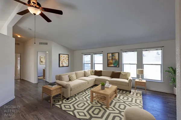 an empty room with wooden floor fan and windows