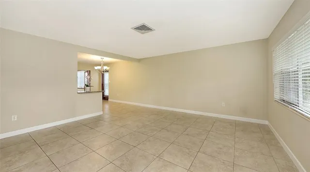 an empty room with kitchen view and a window