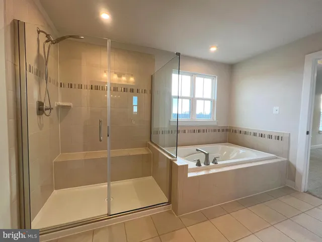 a bathroom with a tub a sink a mirror and a shower