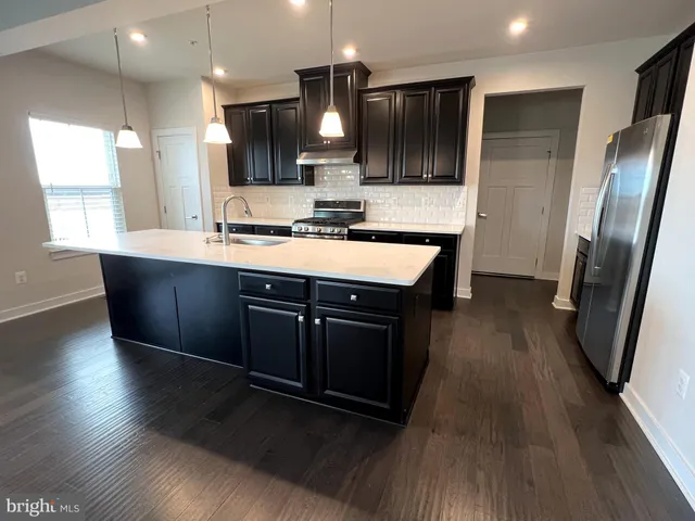 a kitchen with stainless steel appliances granite countertop wooden floors wooden cabinets a sink and a stove