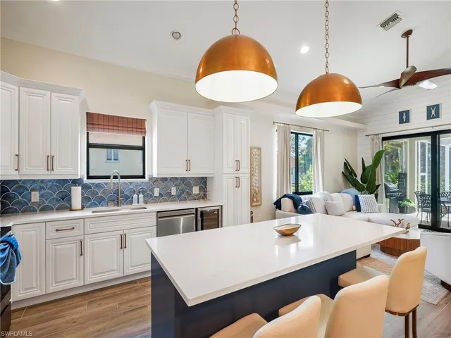 a living room with furniture kitchen view and a large window