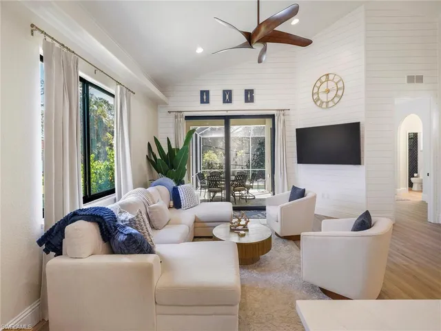 a living room with couches a flat screen tv and a large window