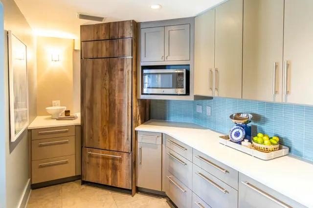 a utility room with stainless steel appliances white cabinets and a refrigerator
