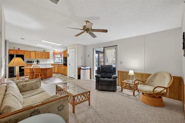 a living room with furniture kitchen view and a chandelier