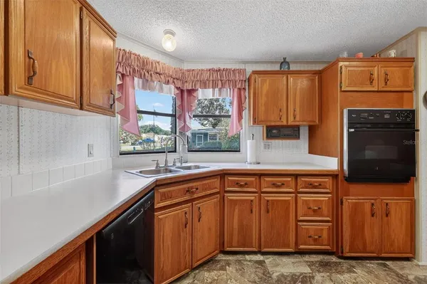 a kitchen with stainless steel appliances granite countertop a sink a stove cabinets counter space and a window