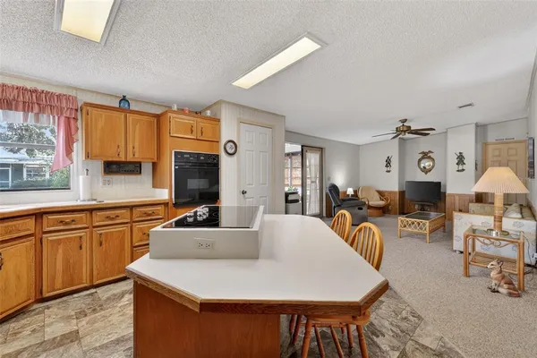 a large kitchen with cabinets a sink dishwasher a dining table and chairs with wooden floor