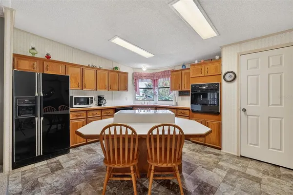 a kitchen with stainless steel appliances granite countertop a refrigerator a stove a sink a dining table and chairs with wooden floor