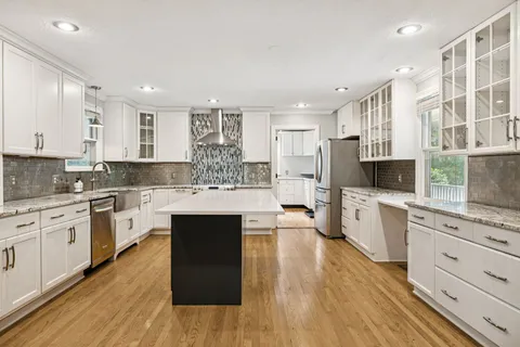 a large kitchen with cabinets wooden floor and stainless steel appliances