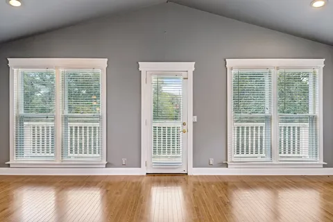a view of empty room with wooden floor and windows