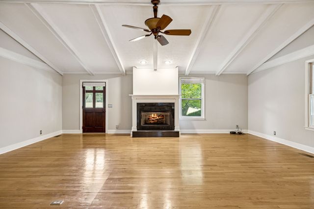 a view of an empty room with a fireplace and a chandelier fan