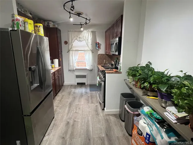 a kitchen with stainless steel appliances a refrigerator a sink a stove and white cabinets