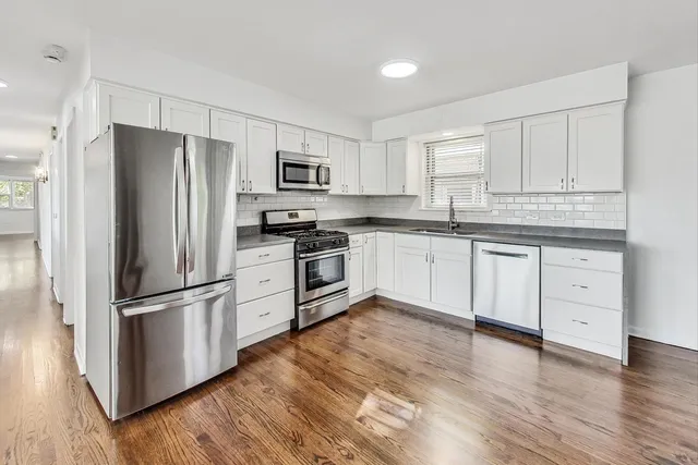 a kitchen with white cabinets stainless steel appliances and wooden floor