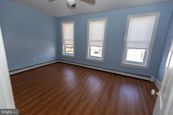 a view of an empty room with wooden floor and window