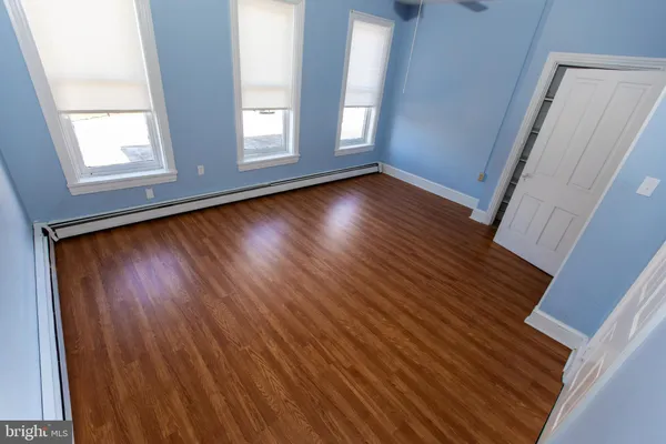 an empty room with wooden floor and windows