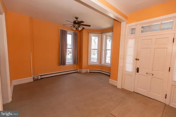 an empty room with windows and chandelier fan