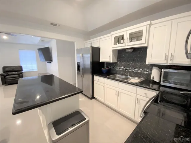 a kitchen with stainless steel appliances kitchen island granite countertop a table chairs and a refrigerator