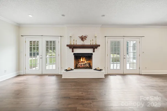 a view of an empty room with wooden floor and a fireplace