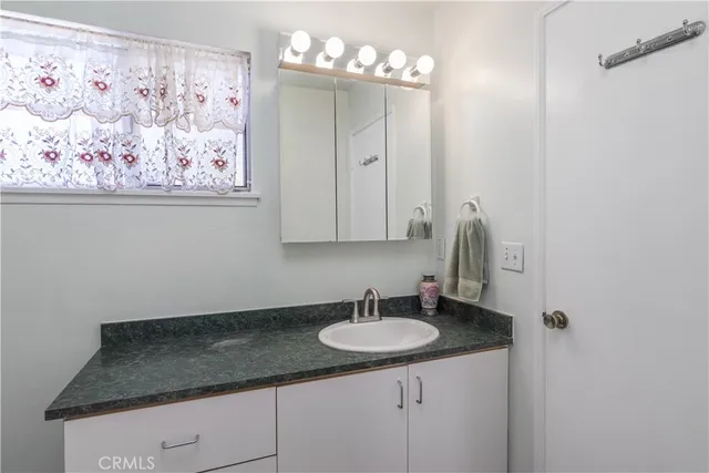 a bathroom with a granite countertop sink and a mirror
