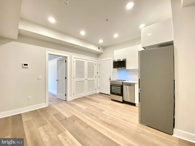 a view of a electric appliances in kitchen and empty room with wooden floor