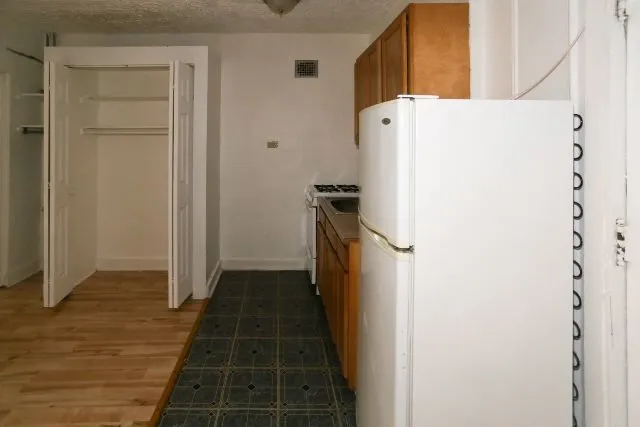 a view of a kitchen with refrigerator and window