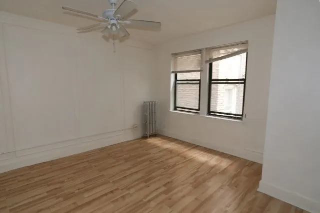 an empty room with wooden floor fan and windows