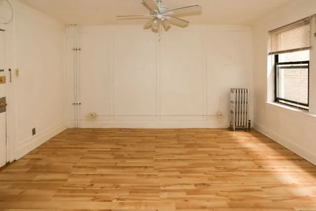 a view of an empty room with window and wooden floor