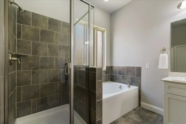 a bathroom with a double vanity sink a large mirror a bathtub and next to a window