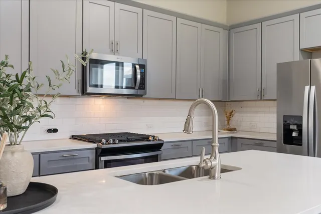 a kitchen with stainless steel appliances granite countertop white cabinets a microwave a sink and dishwasher