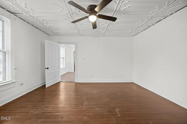 a view of an empty room with window and wooden floor