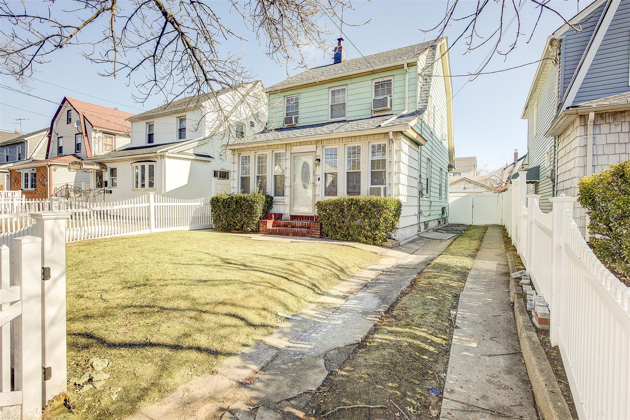 Back of house featuring entry steps, a fenced backyard, a lawn, a residential view, and a chimney