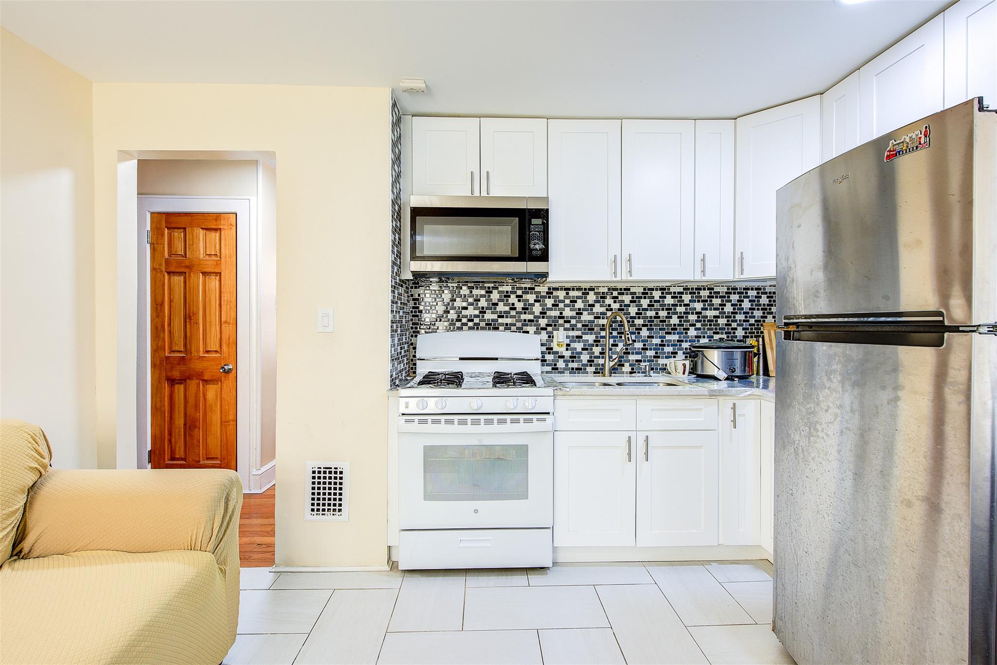 89-91 215th Place Queens, NY 11427 - Photo 11 of 16 Kitchen featuring stainless steel appliances, tasteful backsplash, a sink, and white cabinets