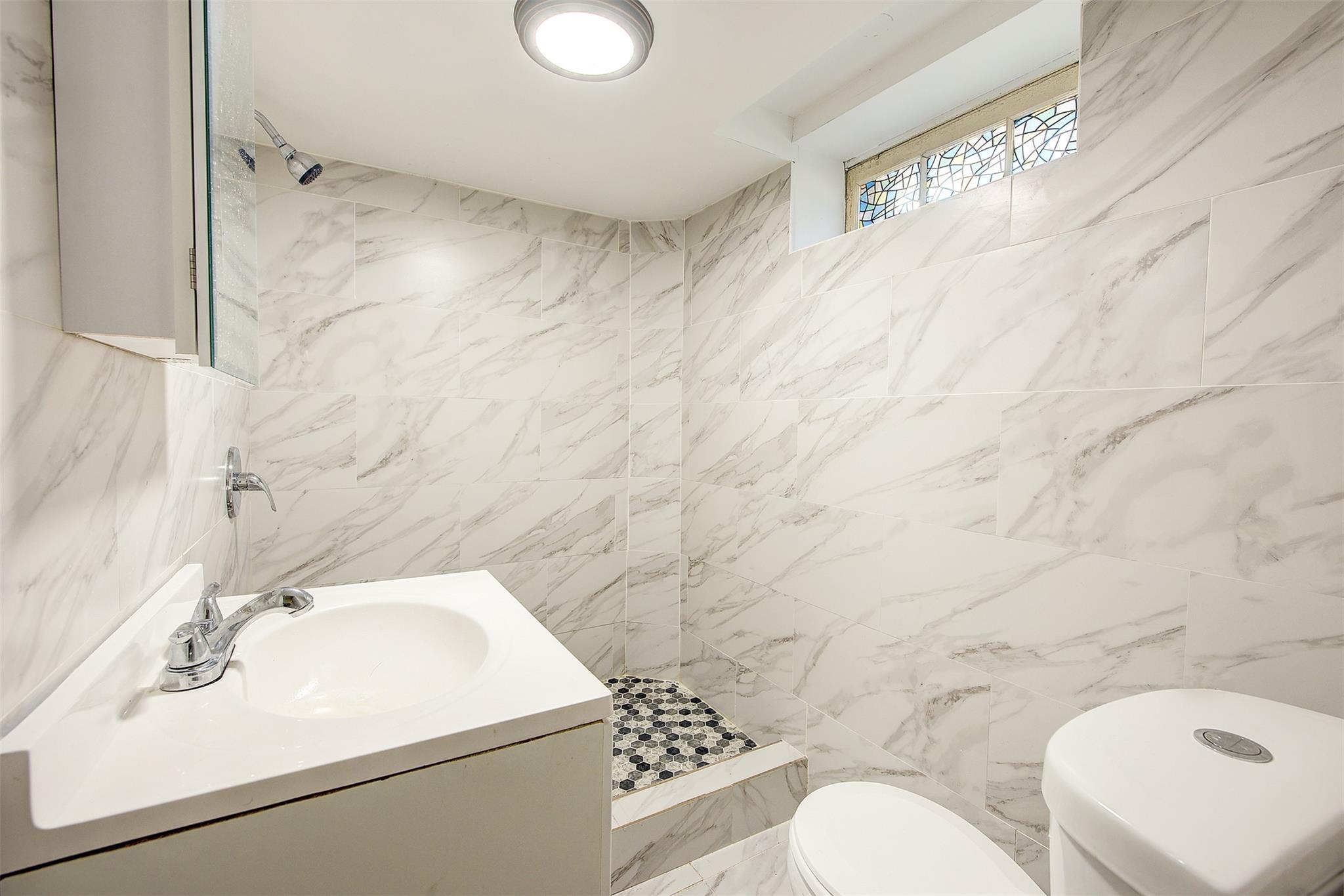 89-91 215th Place Queens, NY 11427 - Photo 8 of 16 Bathroom with vanity, a tile shower, toilet, and tile walls