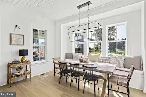 a dining room with wooden floor a chandelier a glass table and chairs