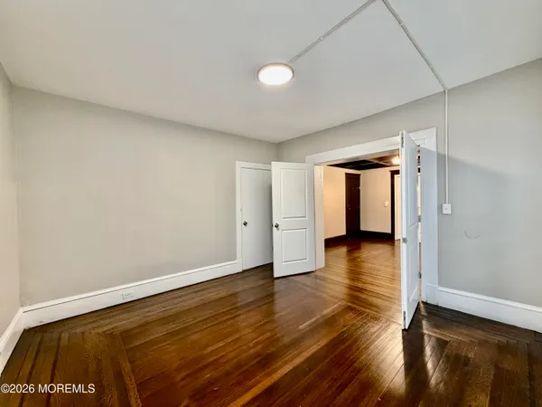 a view of an empty room with wooden floor and closet