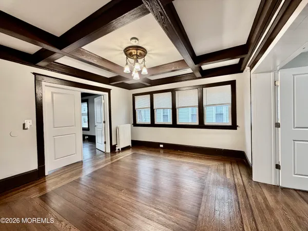 a view of an empty room with wooden floor and a ceiling fan