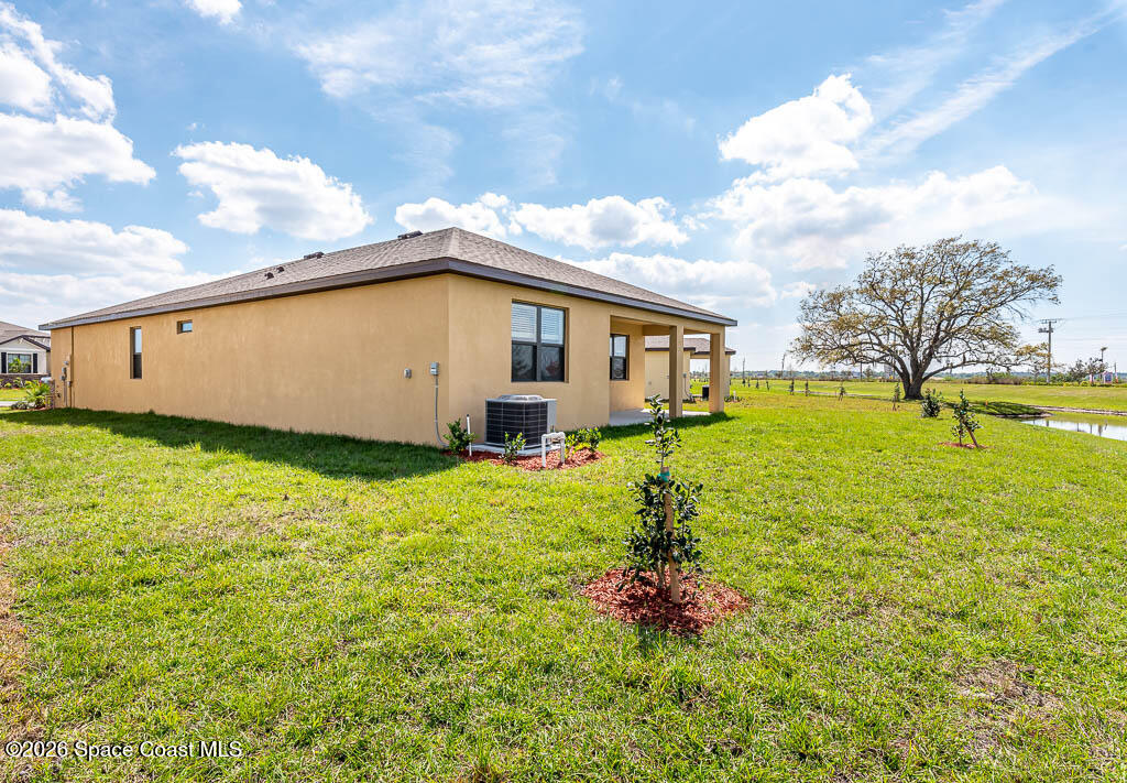 1863 Farmhouse Road Southeast Palm Bay, FL 32909 - Photo 8 of 44 a white house with a big yard and large trees