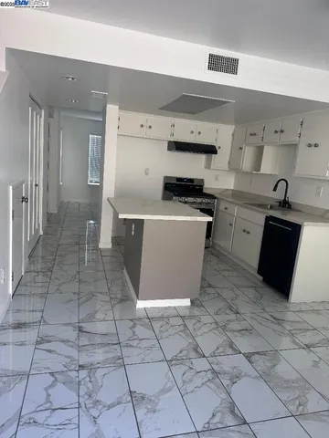 a kitchen with a sink dishwasher and white cabinets with wooden floor