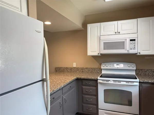 a kitchen with granite countertop white cabinets and white appliances