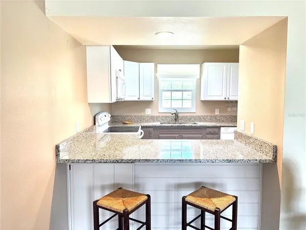 a kitchen with stainless steel appliances granite countertop a sink window and cabinets