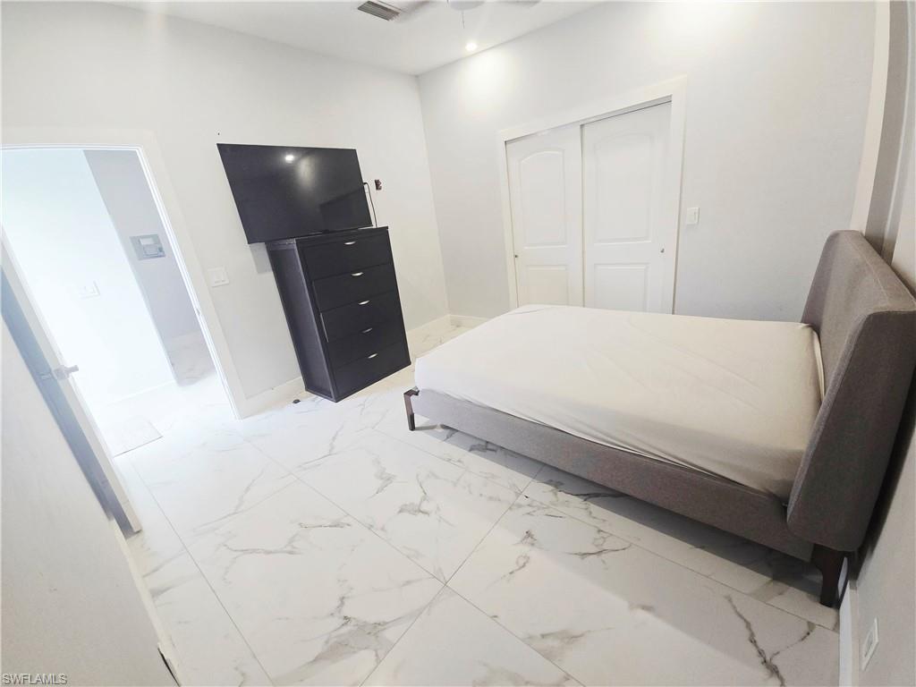 5321 Warren Street Naples, FL 34113 - Photo 15 of 21 a bedroom with a bed and a flat screen tv