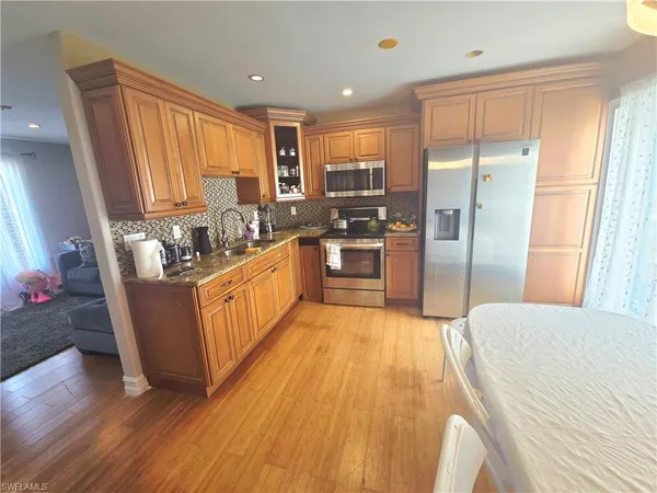 a kitchen with stainless steel appliances a dining table chairs and wooden floor