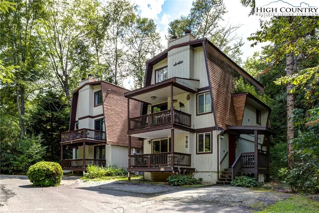 a view of a house with brick walls plants and large tree
