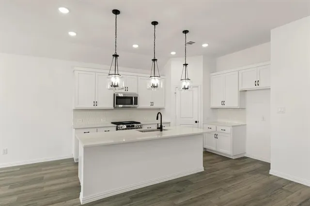 a kitchen with stainless steel appliances white cabinets and wooden floor